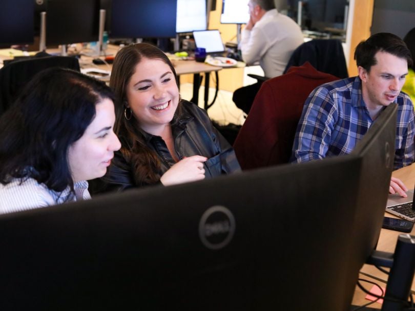Three Zeta Global team members chat while working together in the office on Employee Appreciation Day 2025